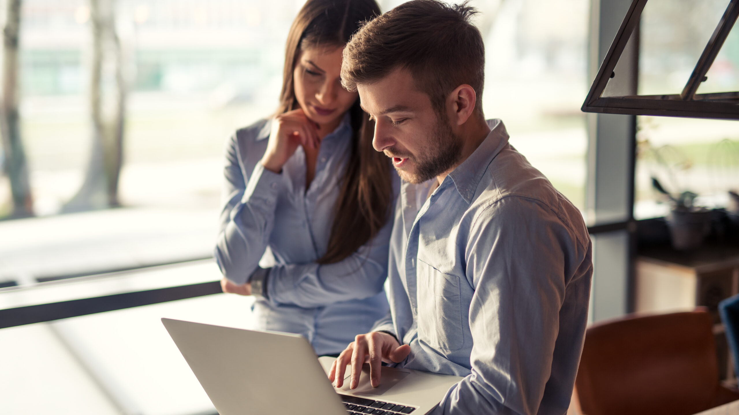 Two colleagues looking at a computer and discussing business.