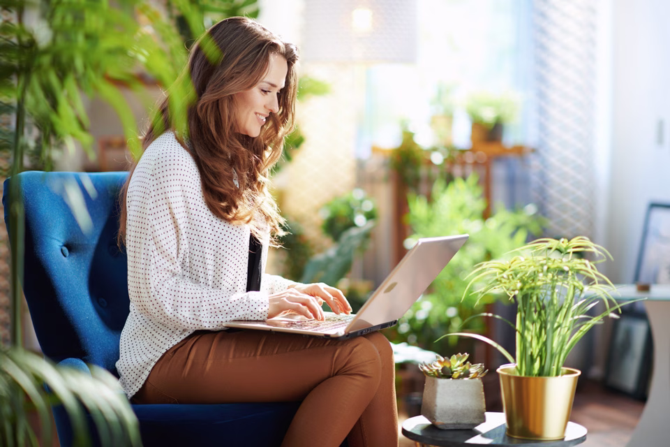 A woman uses her laptop and smiles at the customized experience, showing how it's helpful for retaining existing customers.