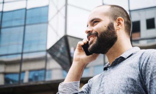 man on the phone smiling after interacting with employees that learned how to improve customer service