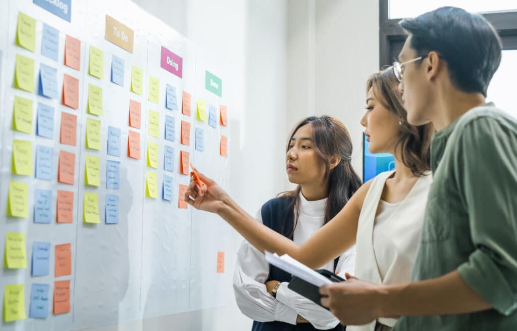 three CX analysts using a whiteboard and sticky notes to track customer and employee satisfaction using the Interaction Quality Score (IQS™).